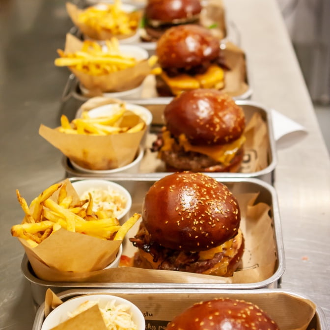 Photo of burgers on plates with sides